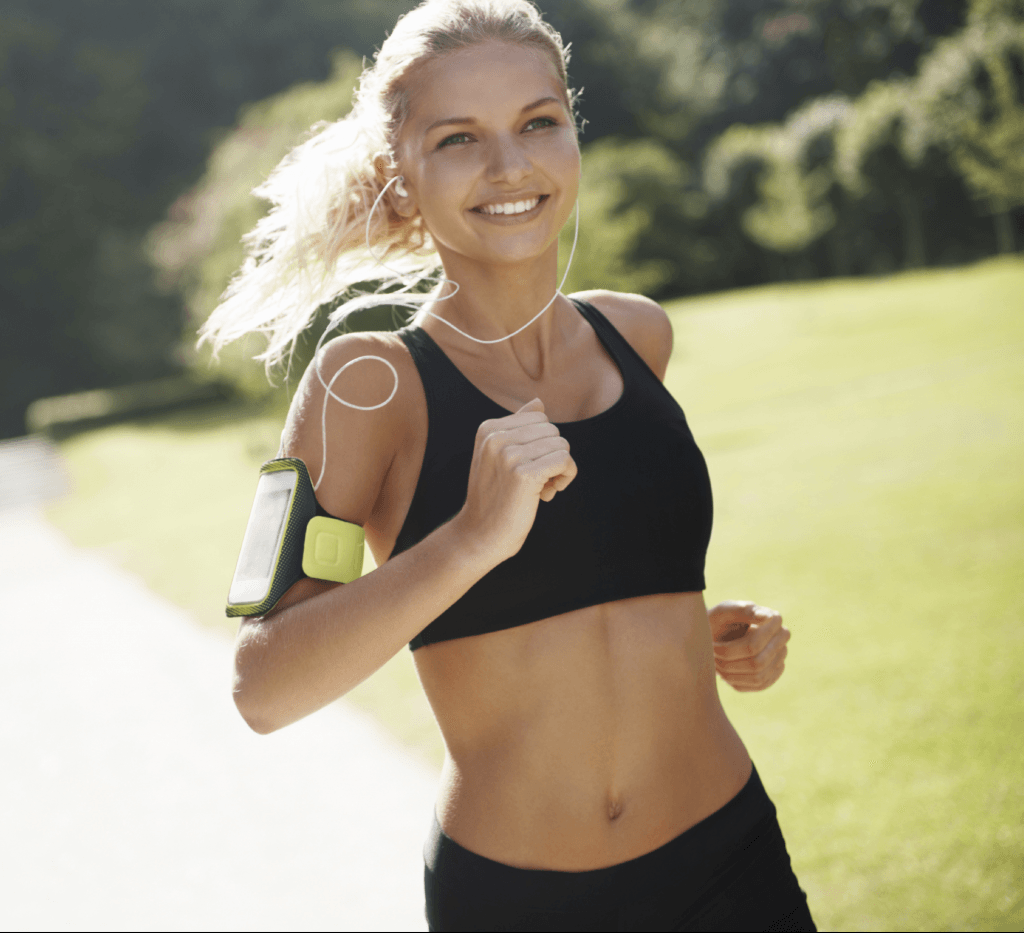 Woman smiling and running with music player strapped to arm