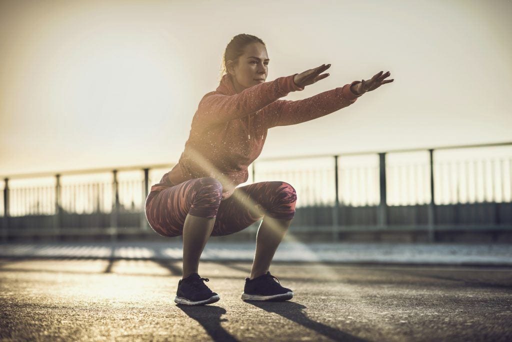 Woman performing a squat while exercising outdoors