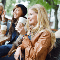 Women laughing together while drinking coffee