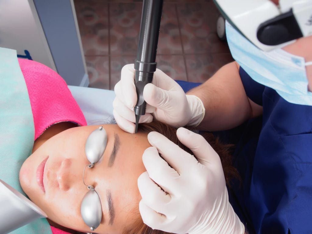 Provider performing a laser skin resurfacing treatment on a woman