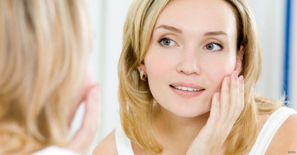 Woman examining her skin in the mirror