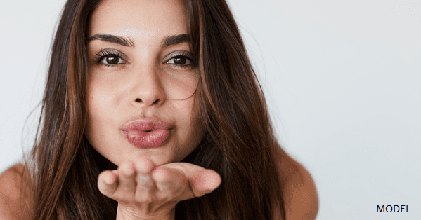 A young brunette woman blowing a kiss