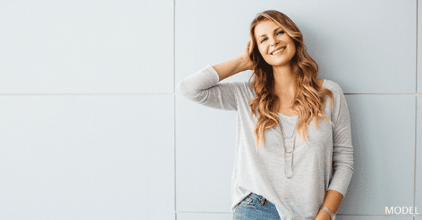 A young blonde woman smiling in a grey top