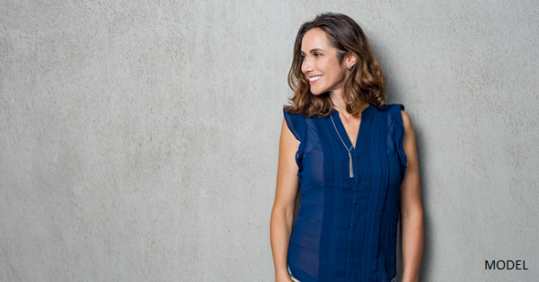 A young brunette woman smiling in a blue top