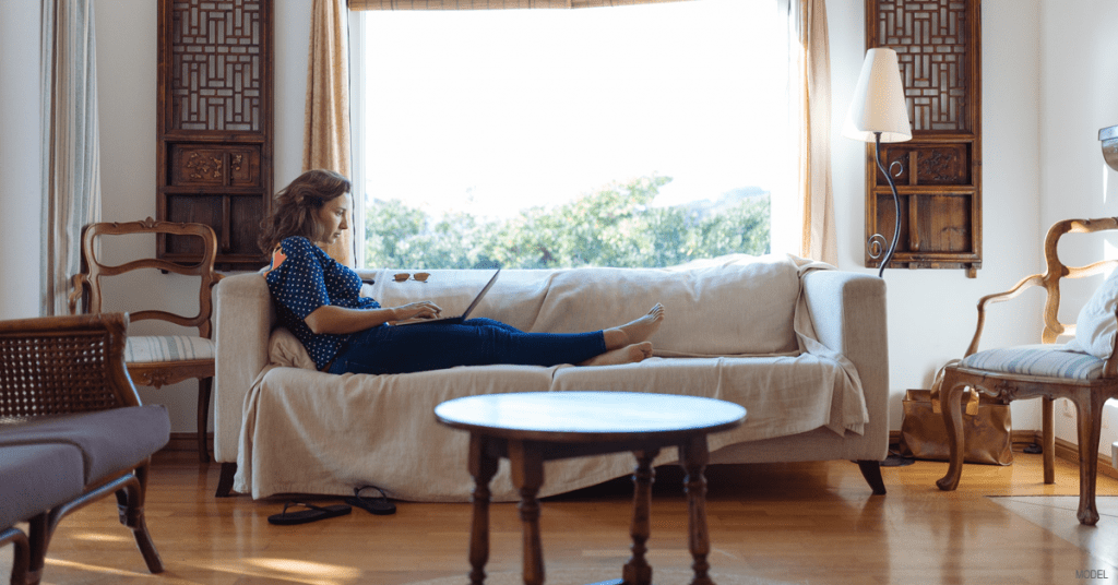 Woman resting on couch during tummy tuck recovery